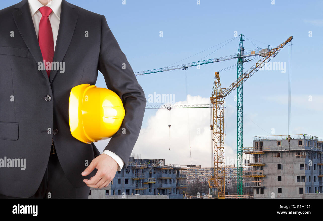 Ingenieur im schwarzen Anzug mit gelben Helm auf der Baustelle Stockfoto