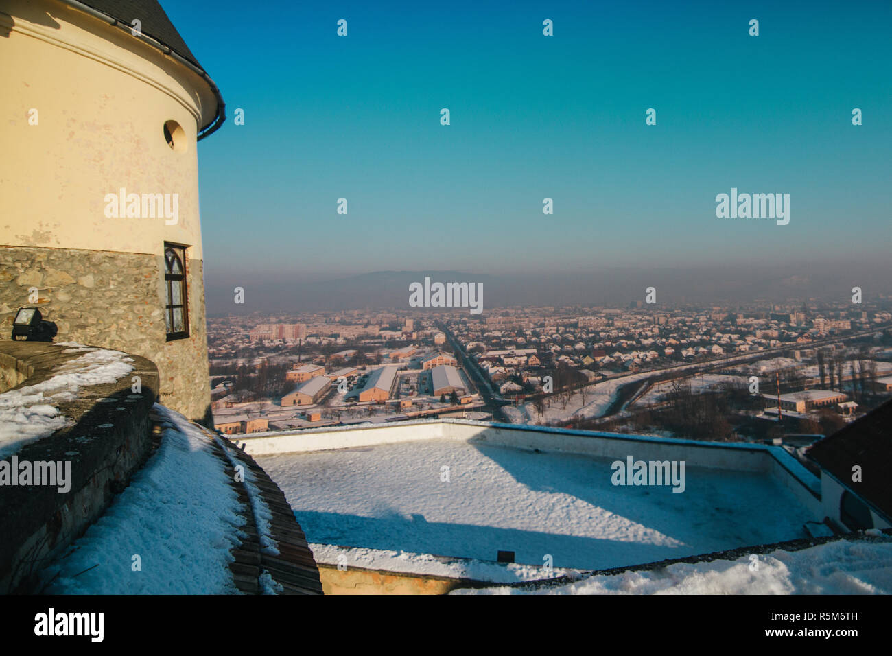 Palanok schloss, überlagert mit Schnee und Mukatschewo Stadtbild auf Hintergrund Stockfoto