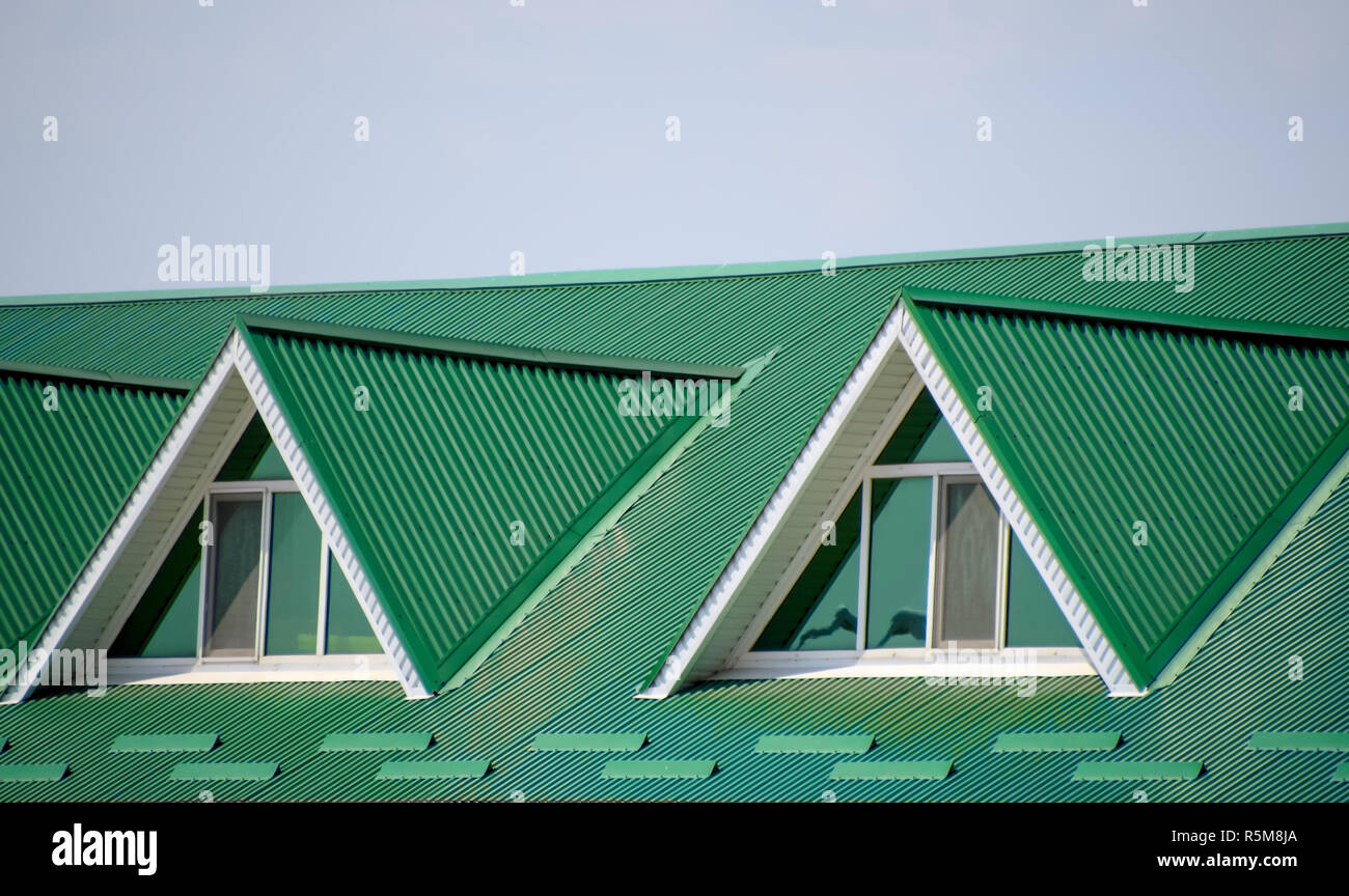 Das Haus mit Kunststoff Fenstern und einem grünen Dach aus Wellblech. Das grüne Dach Wellblech Profil und Kunststoff Fenster. Stockfoto