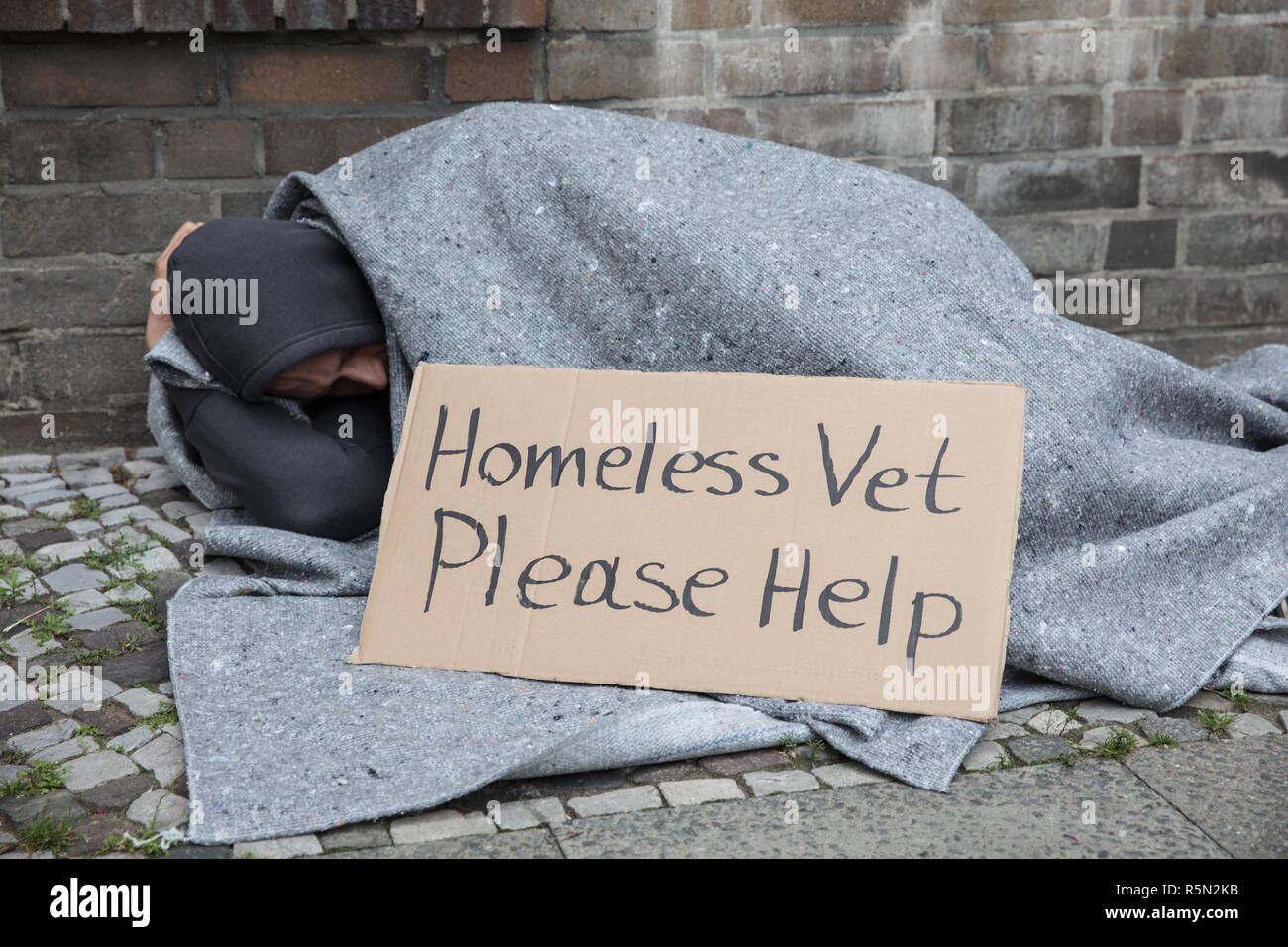 Männliche Obdachlose sitzen auf der Straße um Hilfe zu bitten Stockfoto