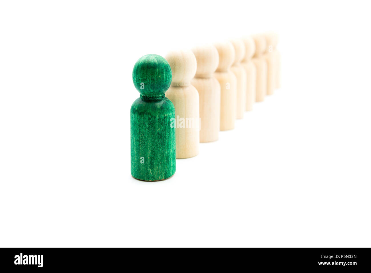 Grün Abbildung stehen heraus von der Masse vor der Linie der Holzfiguren, auf weißem Hintergrund. Führung Konzept Stockfoto