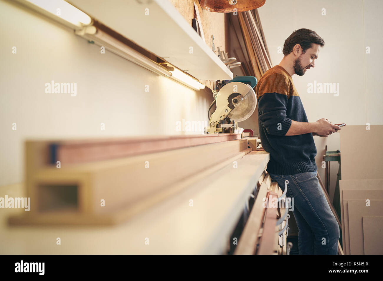 Handwerker mit Handy in seiner Werkstatt Stockfoto