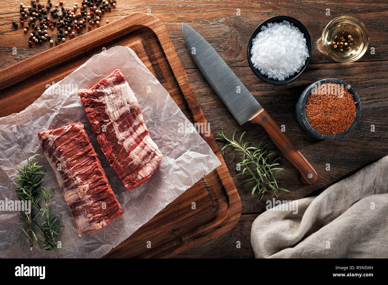 Raw Kalb skirt Steak Fleisch auf weißem kochen Papier und Holz Schneidebrett. Mit Kräutern, Gewürzen und kochmesser eingerichtet. Ansicht von oben. Stockfoto