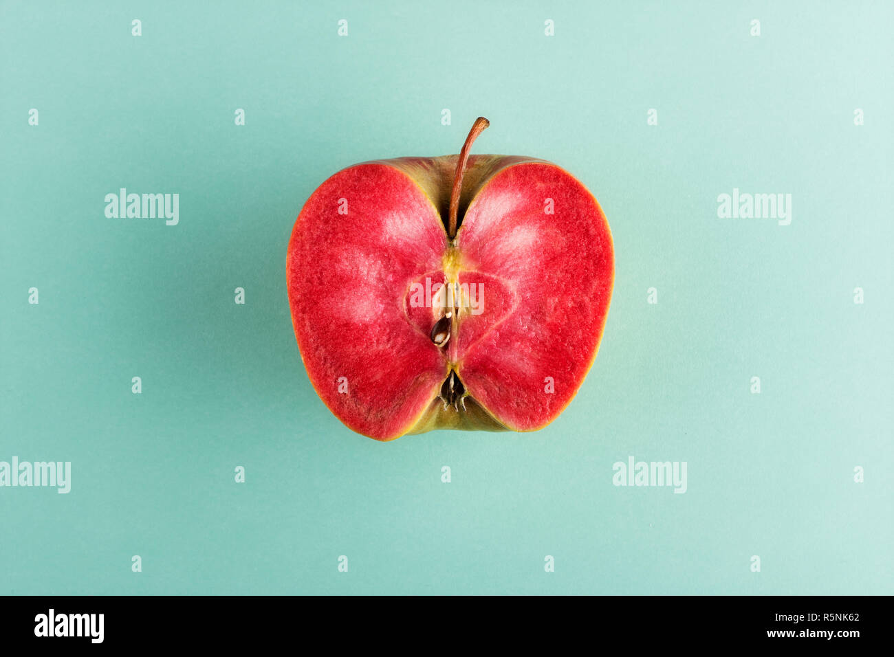 In der halben Apfel Obst mit leuchtend rote Fleisch auf der cyanfarbenen Hintergrund isoliert in Scheiben geschnitten, in Zentrum Stockfoto