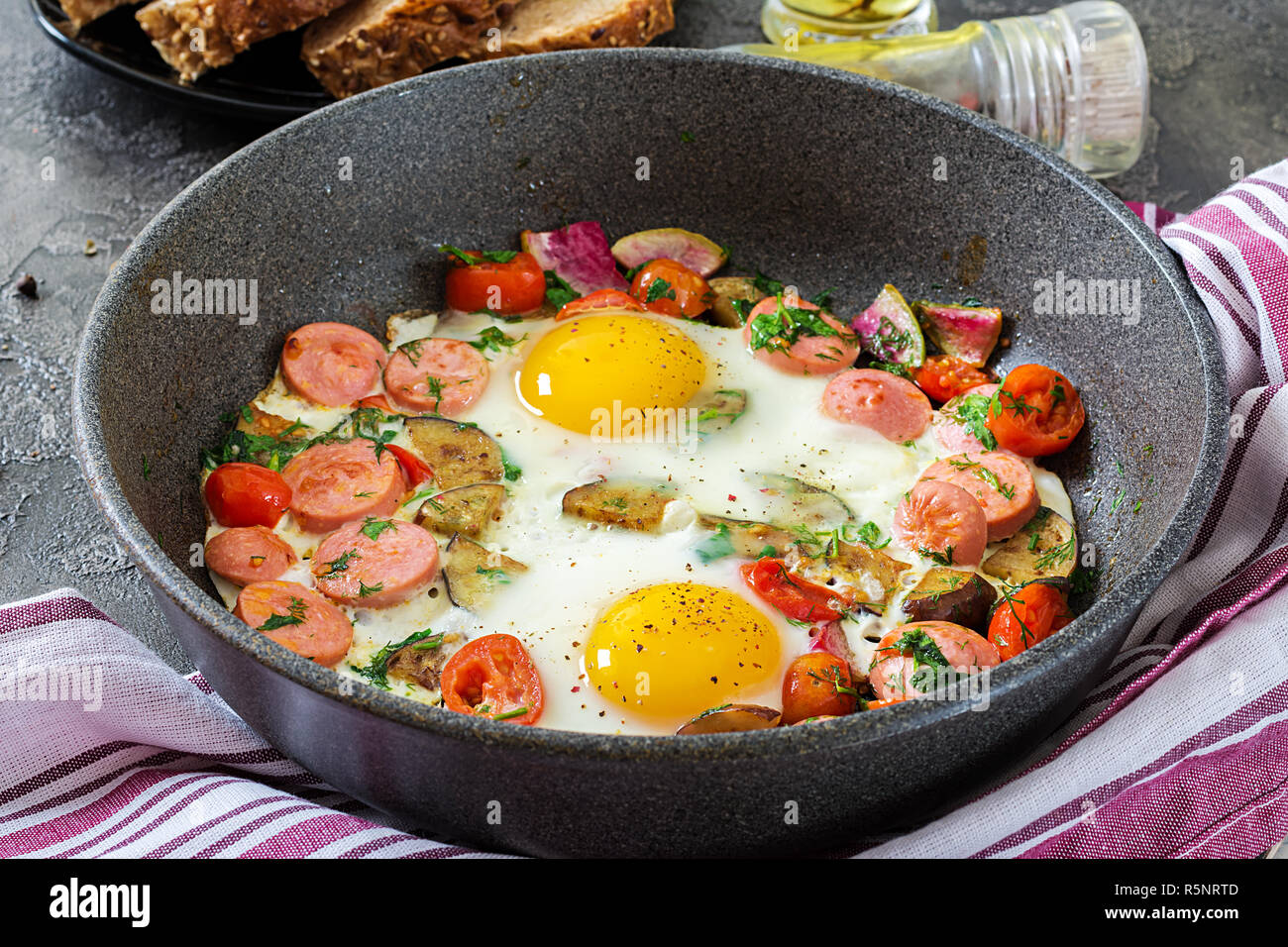 Pfanne mit lecker gekochte Eier, Würstchen und Gemüse auf grau Tabelle.  Frühstück Stockfotografie - Alamy