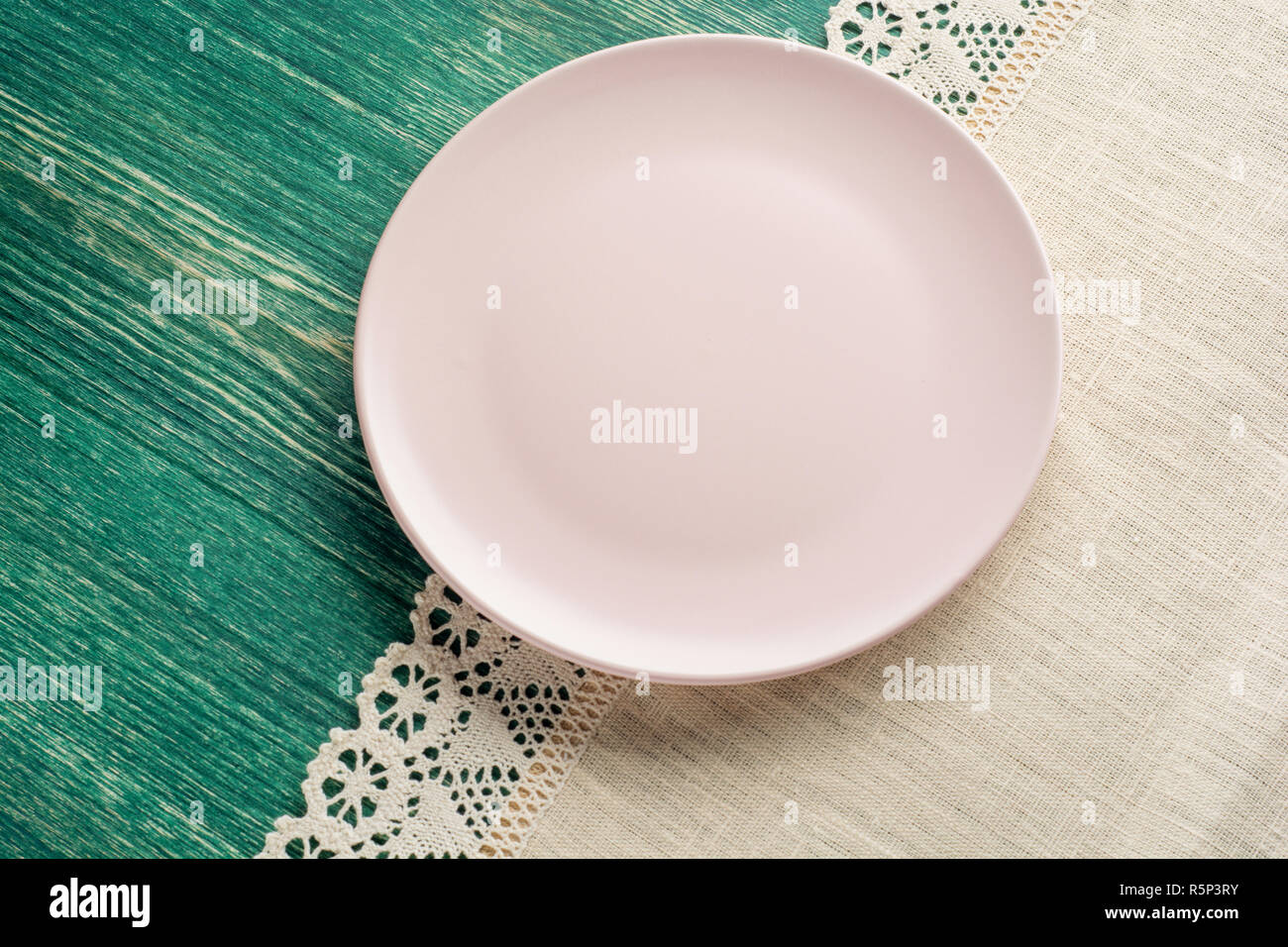 Leere rosa Platte auf Tischdecke auf Holztisch. Ansicht von oben. Stockfoto