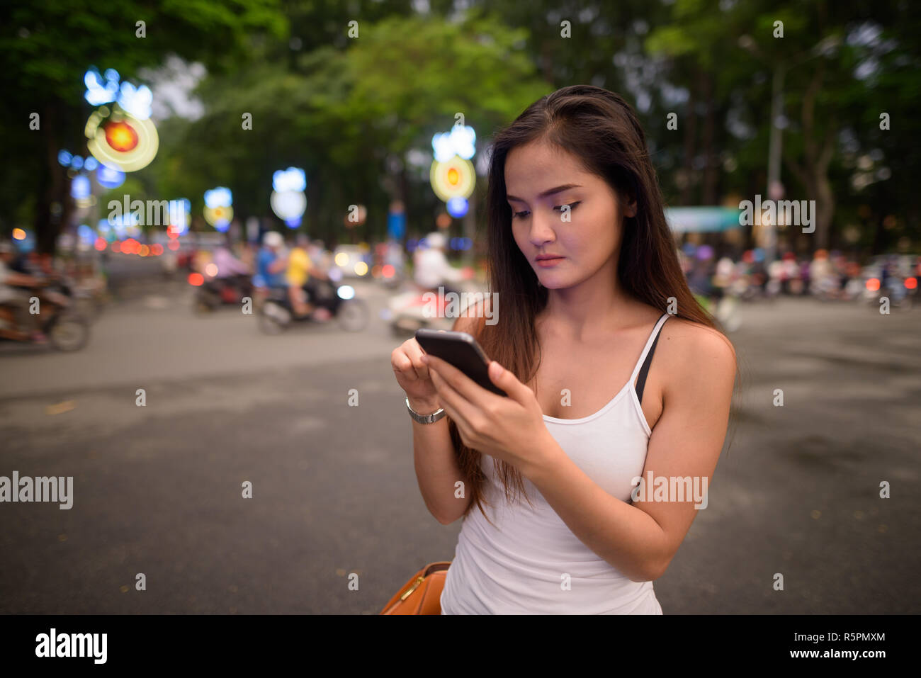 Junge schöne asiatische tourist Frau mit Handy im Freien Stockfoto