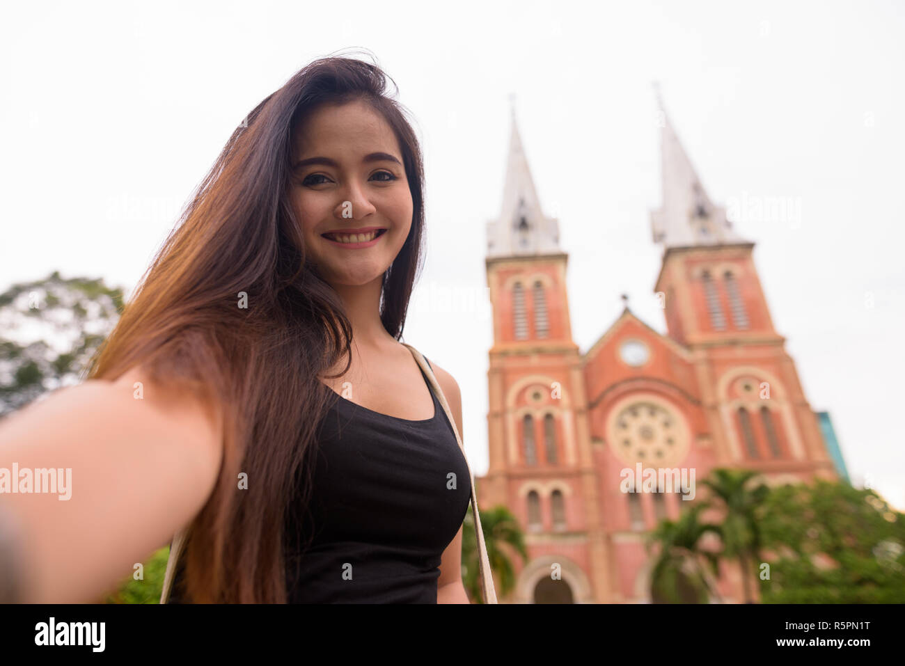Asiatische Frau vor der Kathedrale Notre Dame in Ho Chi Minh City Stockfoto
