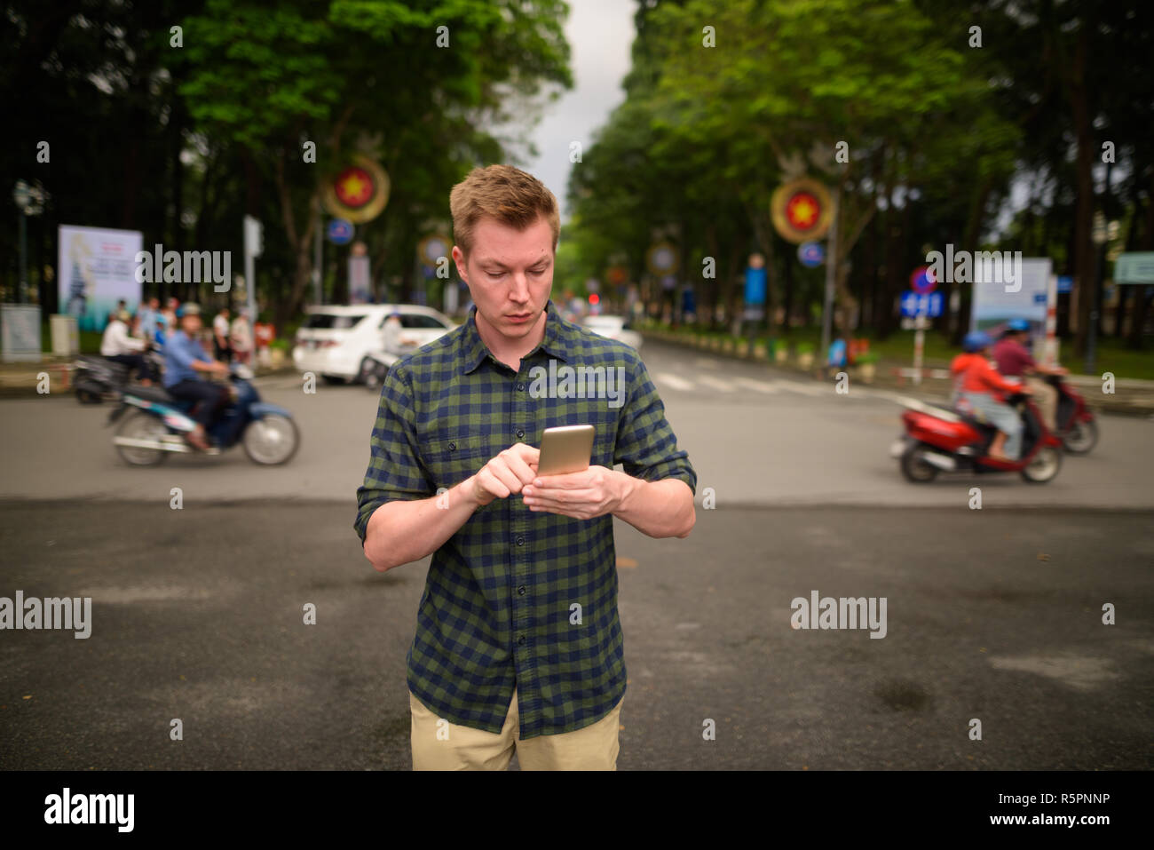 Junge attraktive touristische Mann mit Handy in Vietnam. Stockfoto