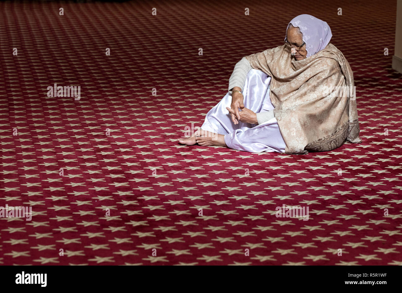 Ein Sikh Frau allein im Gebet und in der Meditation an einem Tempel in Richmond Hill, Queens, New York City Stockfoto