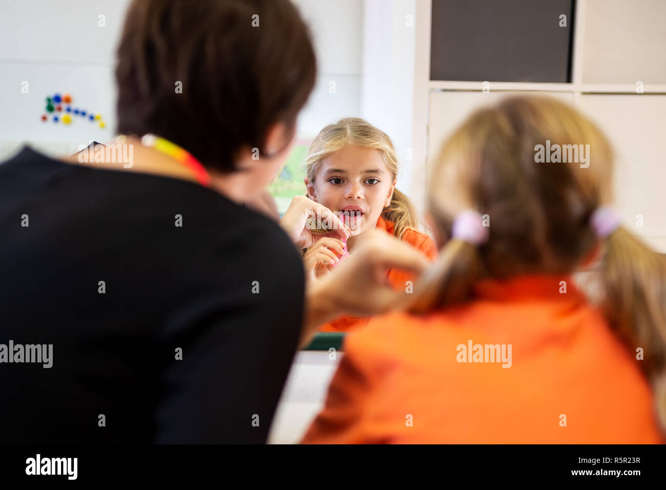 Junge Mädchen in der Sprachtherapie. Spiegelbild der jungen Mädchen trainieren die richtige Aussprache mit der logopädin. Stockfoto
