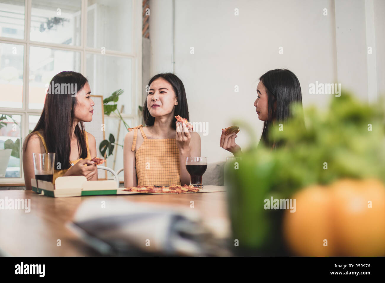 Gruppe von Asiatischen teen Frauen genießen essen Pizza und trinken Limo, nicht gesundes Essen vor der Tabelle zu Hause Pflege Stockfoto