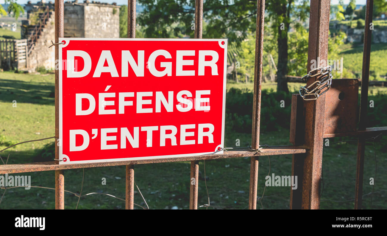 Rote Zeichen auf einem rostigen Tor platziert werden, oder es ist in französischer Sprache Gefahr geschrieben verteidigt eingeben Stockfoto
