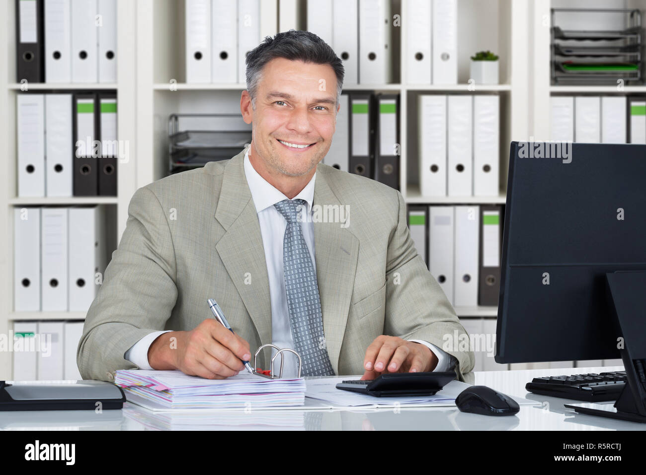 Zuversichtlich Buchhalter mit Rechner beim Schreiben von Dokumenten Stockfoto