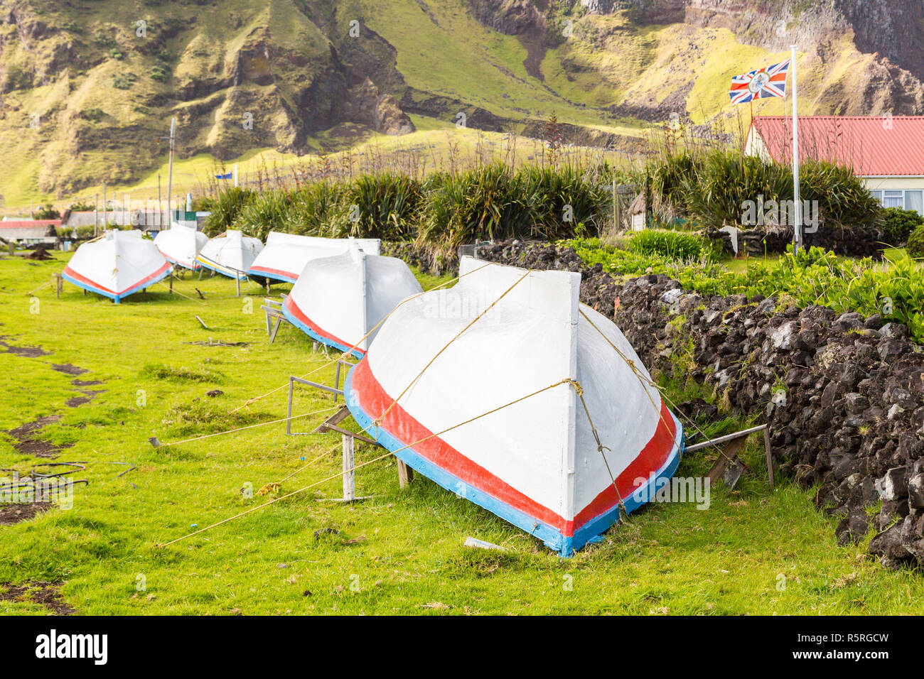 Landschaft Gras Straße mit einer Reihe von Trocknen umgeworfen Boote. Britische Gouverneur Flagge. Edinburgh der Sieben Meere Stadt, Tristan da Cunha. Stockfoto