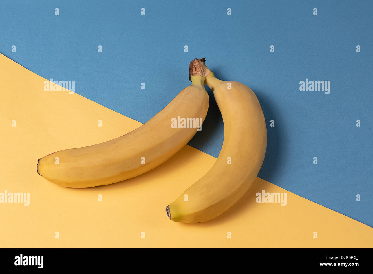Kreative Minimalismus Konzept. Unerwartete Konzept. Flach auf Banane Obst Muster über bunten blauen und gelben Hintergrund. Stockfoto