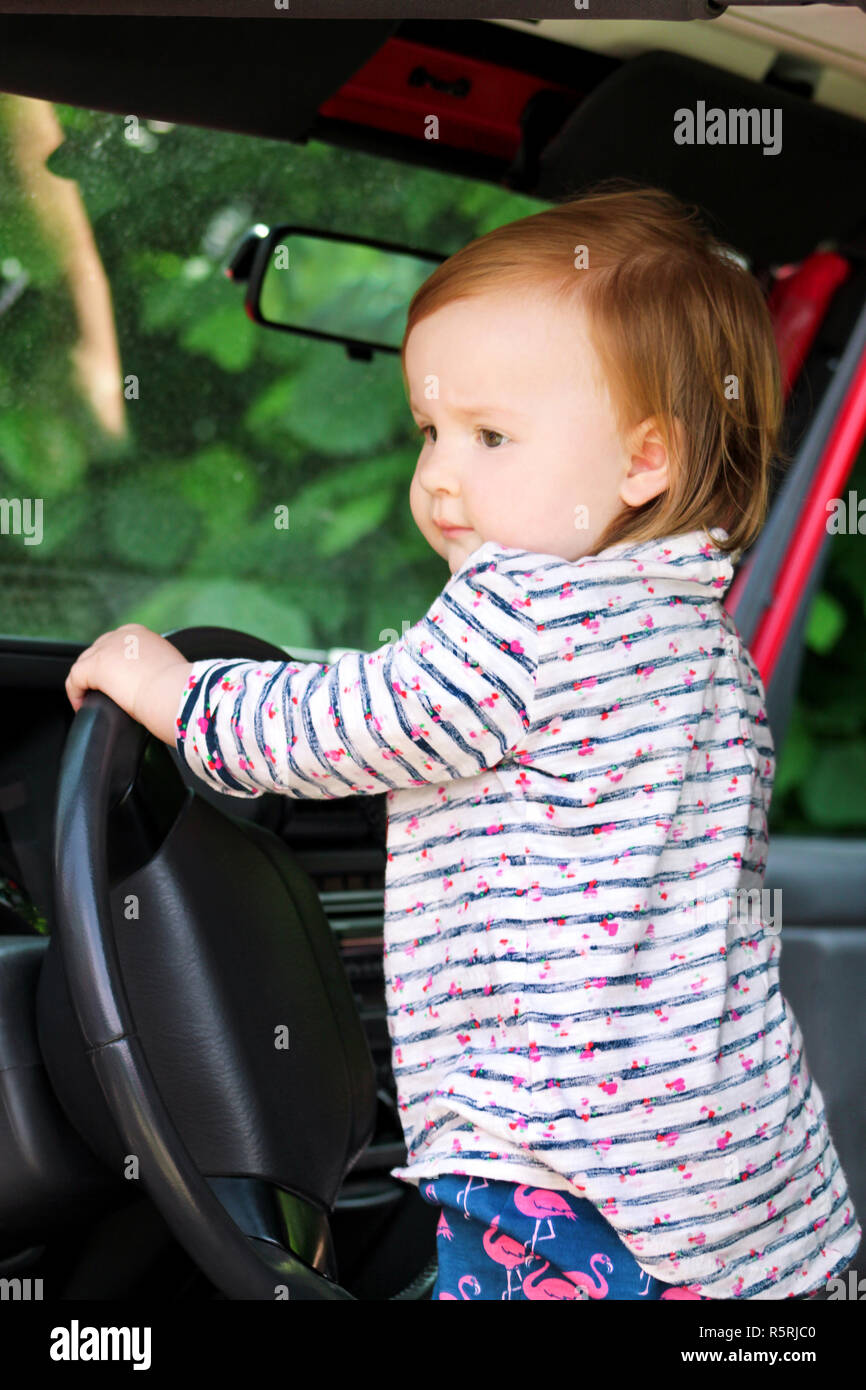 Kinder spielen im Auto Lenkrad. Süße kleine Mädchen fahren Auto