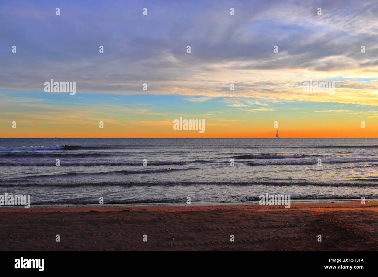 Sonnenaufgang am Strand. Eine Segelyacht im offenen Wasser des Mittelmeers. Lebendige Farben von Daybreak am Malvarrosa Strand, Valencia, Spanien. Stockfoto