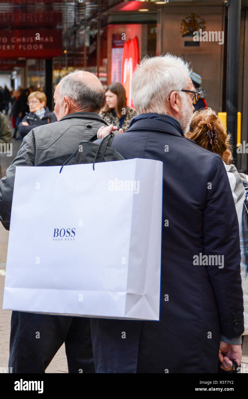 Zwei männliche Käufer an einer geschäftigen Oxford Street, die Hugo Boss Papier tragetaschen auf ihren Schultern Stockfoto