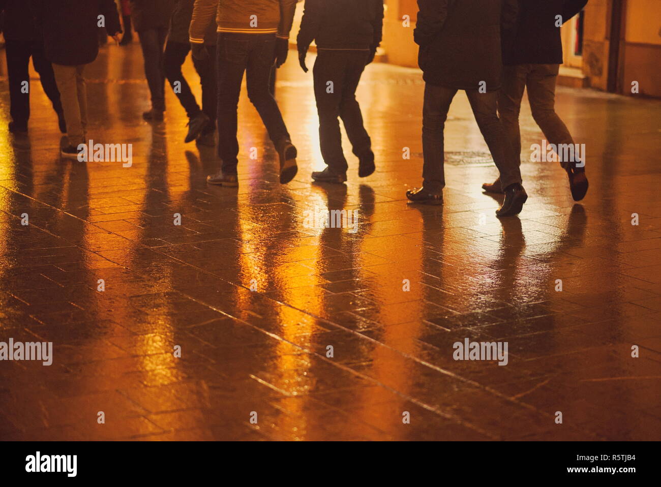 Nasse Straße Pflasterung und Fußgänger Beine in der Nacht Closeup Stockfoto