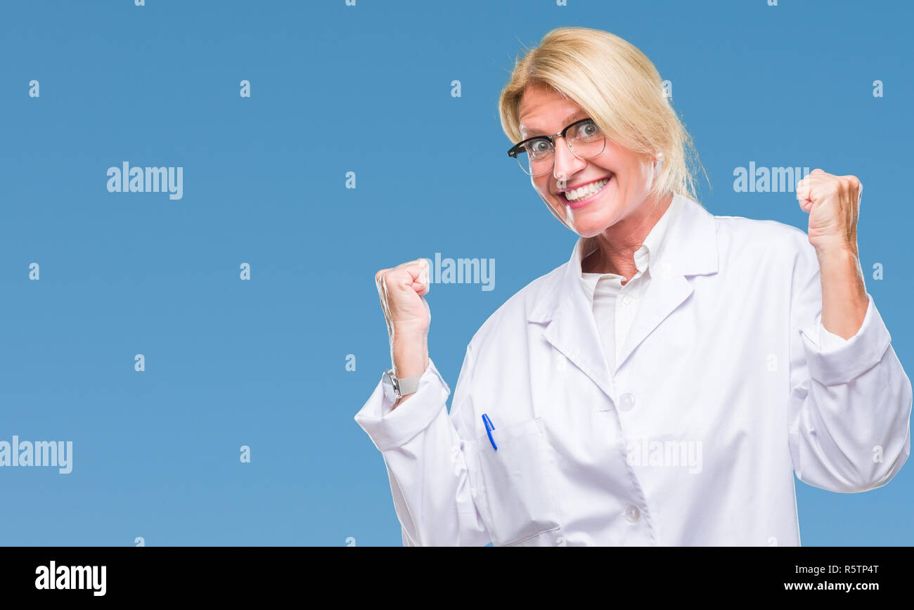 Mittleres Alter blonde Therapeutin Frau tragen weiße Mantel über isolierte Hintergrund sehr glücklich und aufgeregt, Sieger Geste mit erhobenen Armen und lächelte, ein Stockfoto