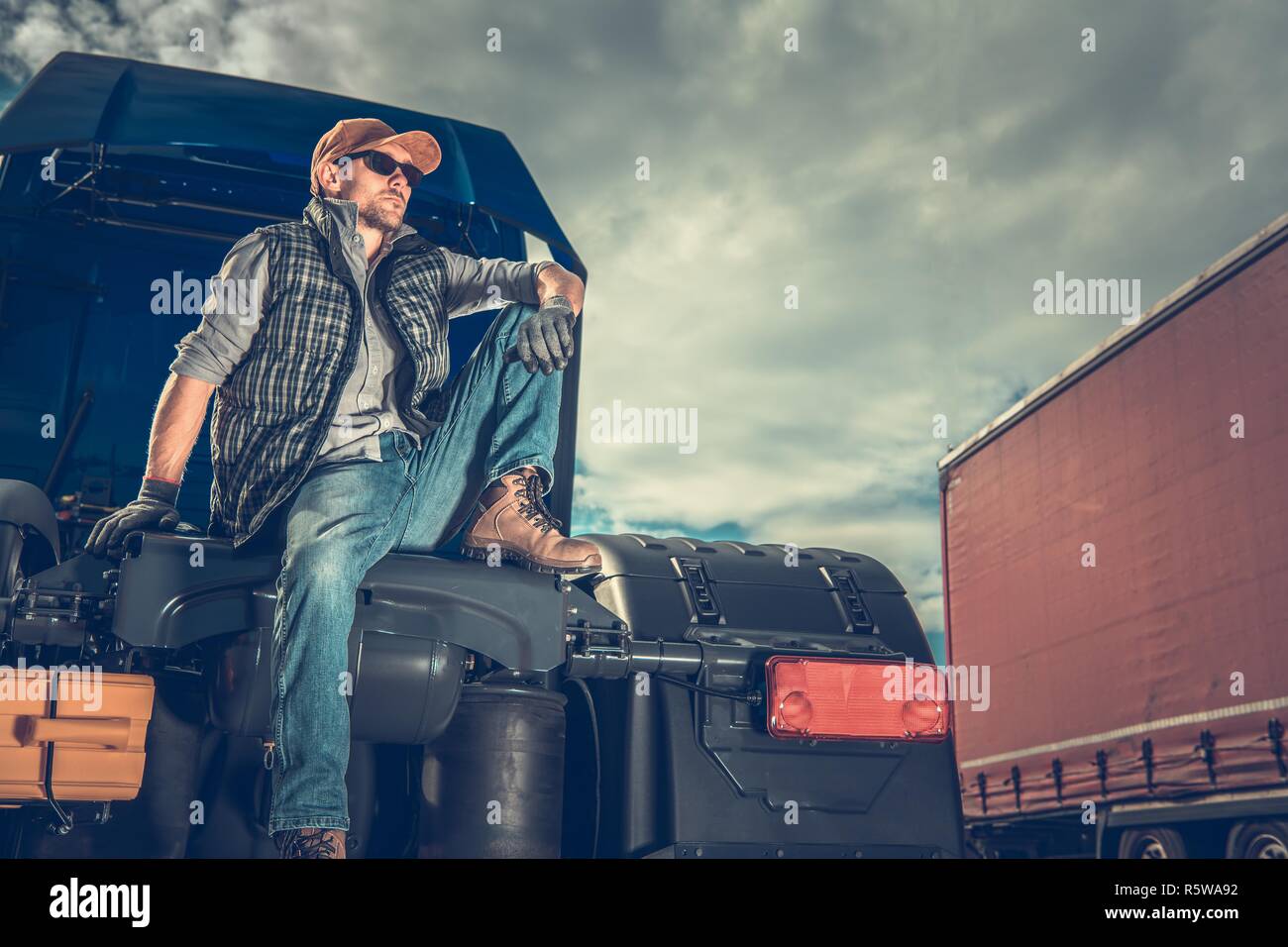 Stolz LKW-Besitzer. Transport- und Logistikunternehmen. Kaukasische Männer Entspannen auf dem Semi Traktor. Stockfoto