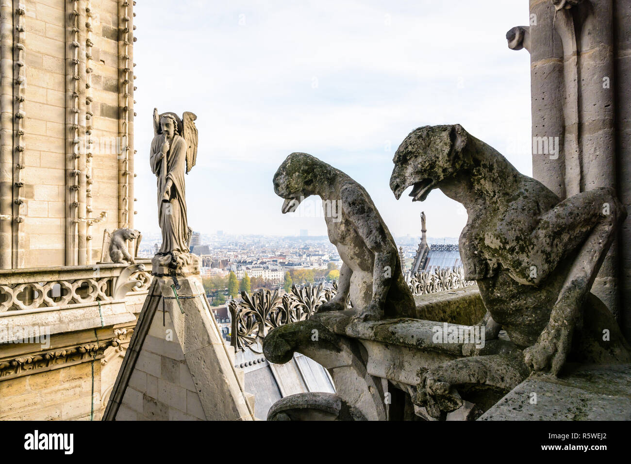 Zwei steinerne Statuen von Chimären mit Blick auf das Dach der Kathedrale Notre-Dame de Paris von den Türmen Galerie mit der Statue von einem Engel mit trumpe Stockfoto