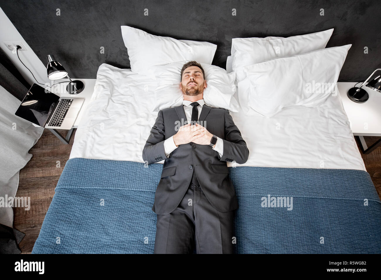 Geschäftsmann im Anzug auf dem Bett liegen wie ein toter Mann im Hotel ...