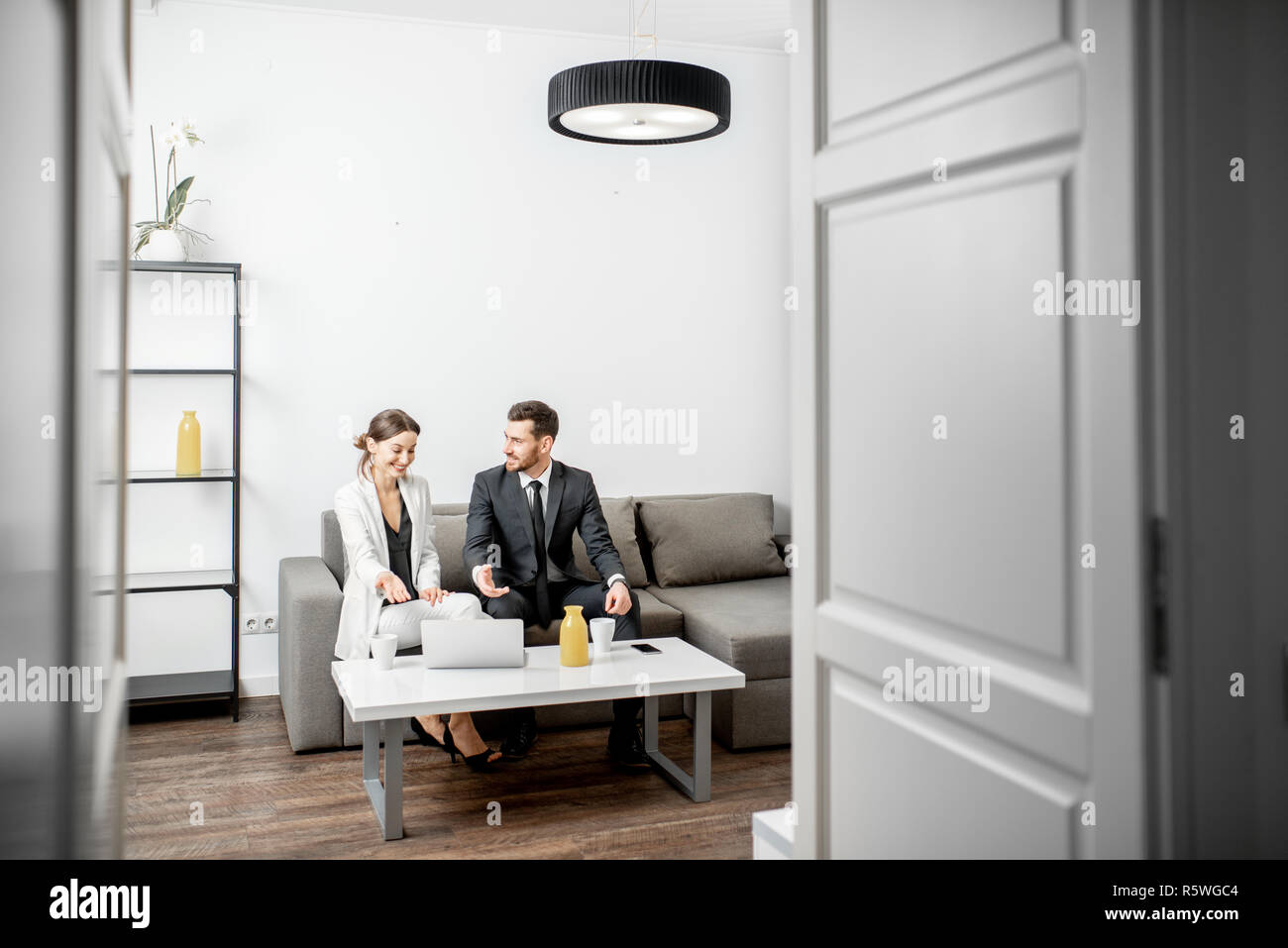 Elegante Geschäftsmann und Frau sitzen zusammen auf der Couch, während der Arbeit mit dem Laptop zu Hause oder im Büro. In der breiten Ansicht mit Kopie Raum Stockfoto