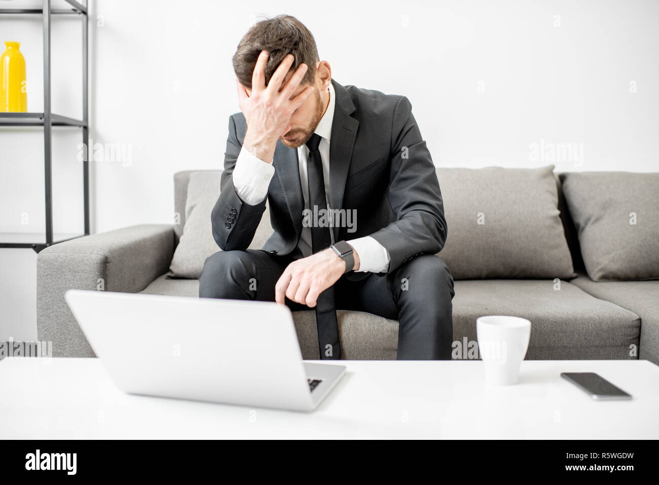 Portrait von ein Geschäftsmann mit Emotionen verwirrt und verzweifelt seinen Kopf sitzen auf der Couch mit dem Laptop Holding Stockfoto