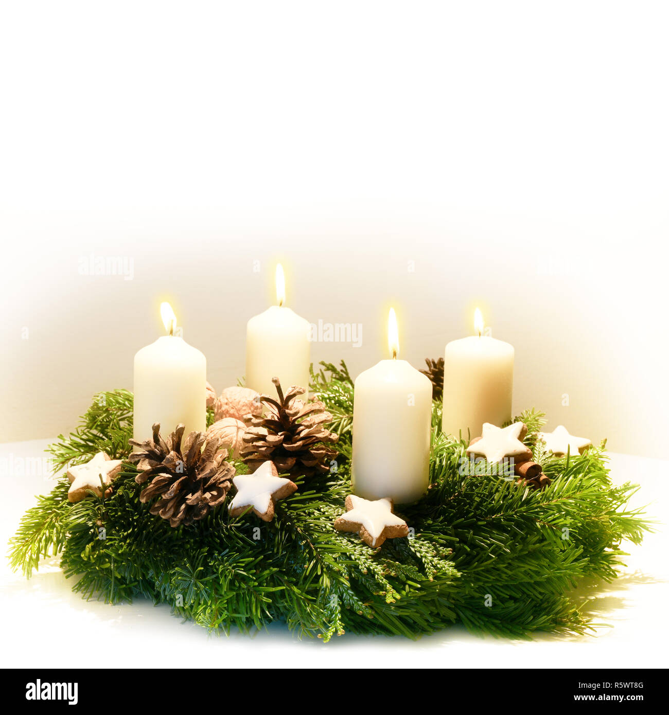 Geschmückt Adventskranz aus Tanne und immergrüne Zweige mit brennenden  weiße Kerzen für die Zeit vor Weihnachten, die hellen Hintergrund verblasst  zu weiss Stockfotografie - Alamy