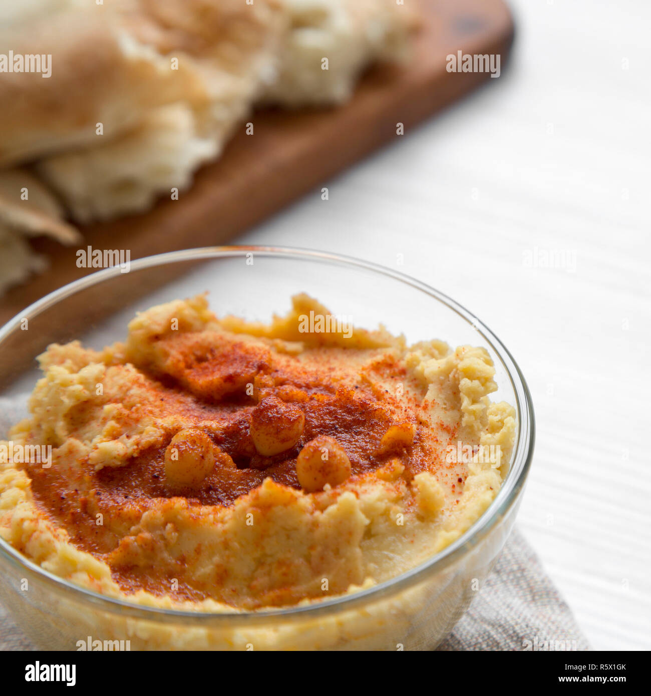 Hummus mit gerösteten Kichererbsen, Paprika, Olivenöl und pita Brot auf einem weißen Hintergrund Holz, Seitenansicht. Nahaufnahme. Stockfoto