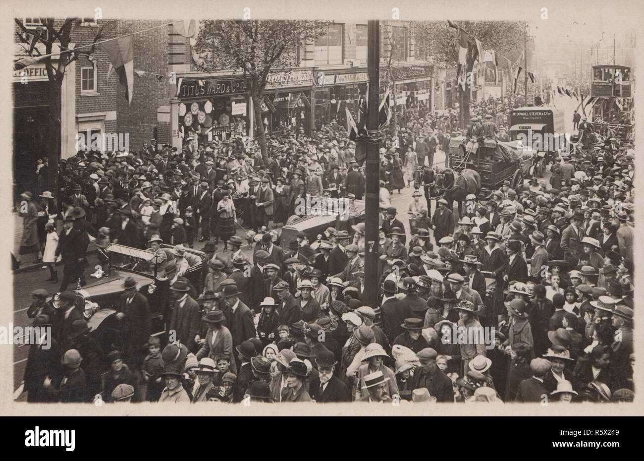 Vintage British photographische Postkarte zeigt eine große öffentliche Veranstaltung mit einer Prozession von Autos und von Pferden gezogene Fahrzeuge. Eines der sichtbaren Geschäfte ist Titus Ward & Co. Ltd., eines der Fahrzeuge hat ein Zeichen für McDowall Steven & Co Ltd. Stockfoto