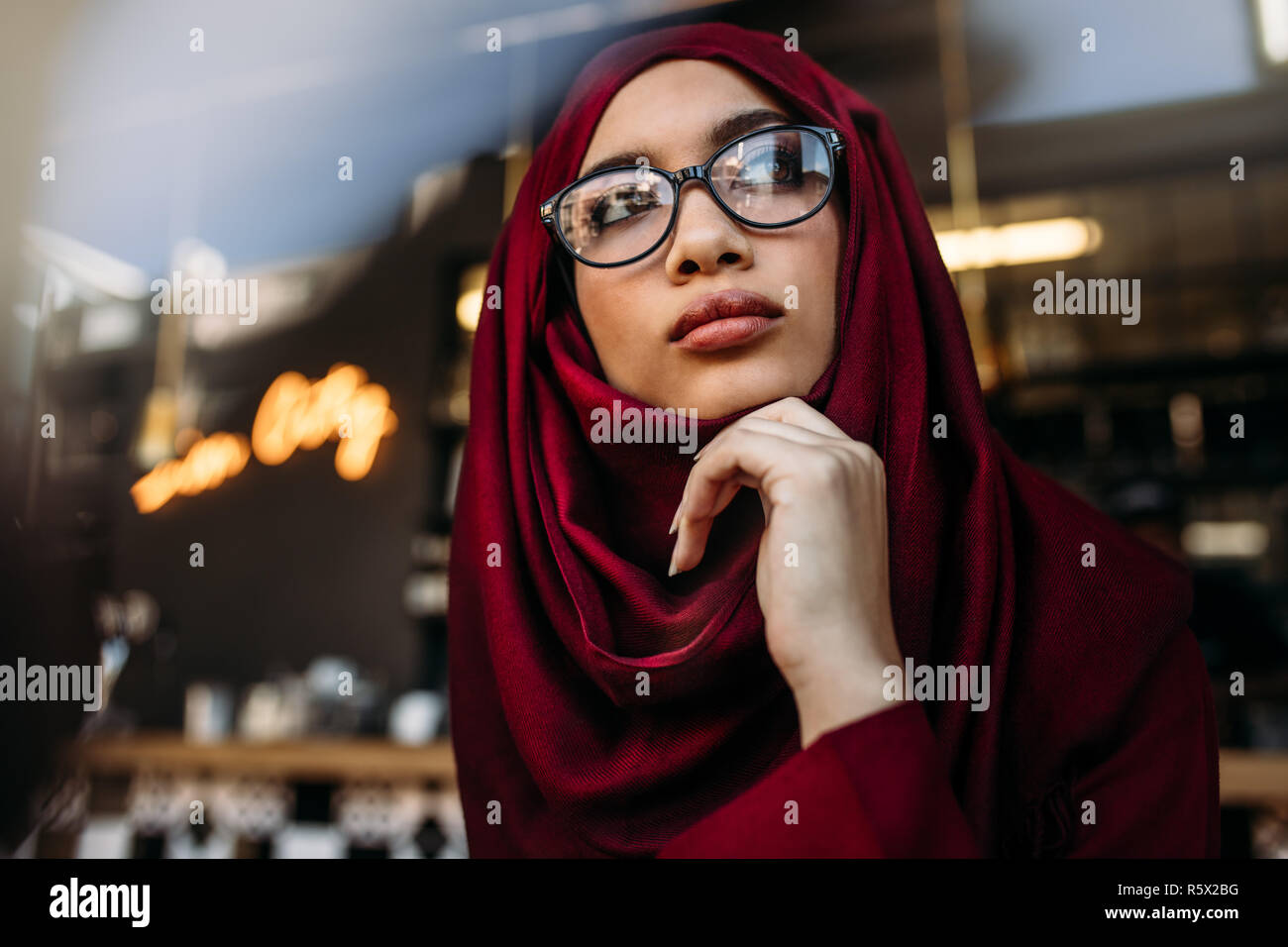 Die islamische Frau in Hijab und Brillen weg schauen mit der Hand am Kinn. Nachdenkliche Frau im hijab weg schauen. Stockfoto