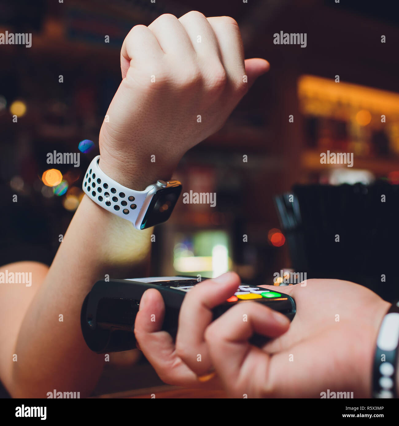 Zugeschnittenes Bild der weiblichen Kunden zahlen über Smart Watch an der Bar Stockfoto