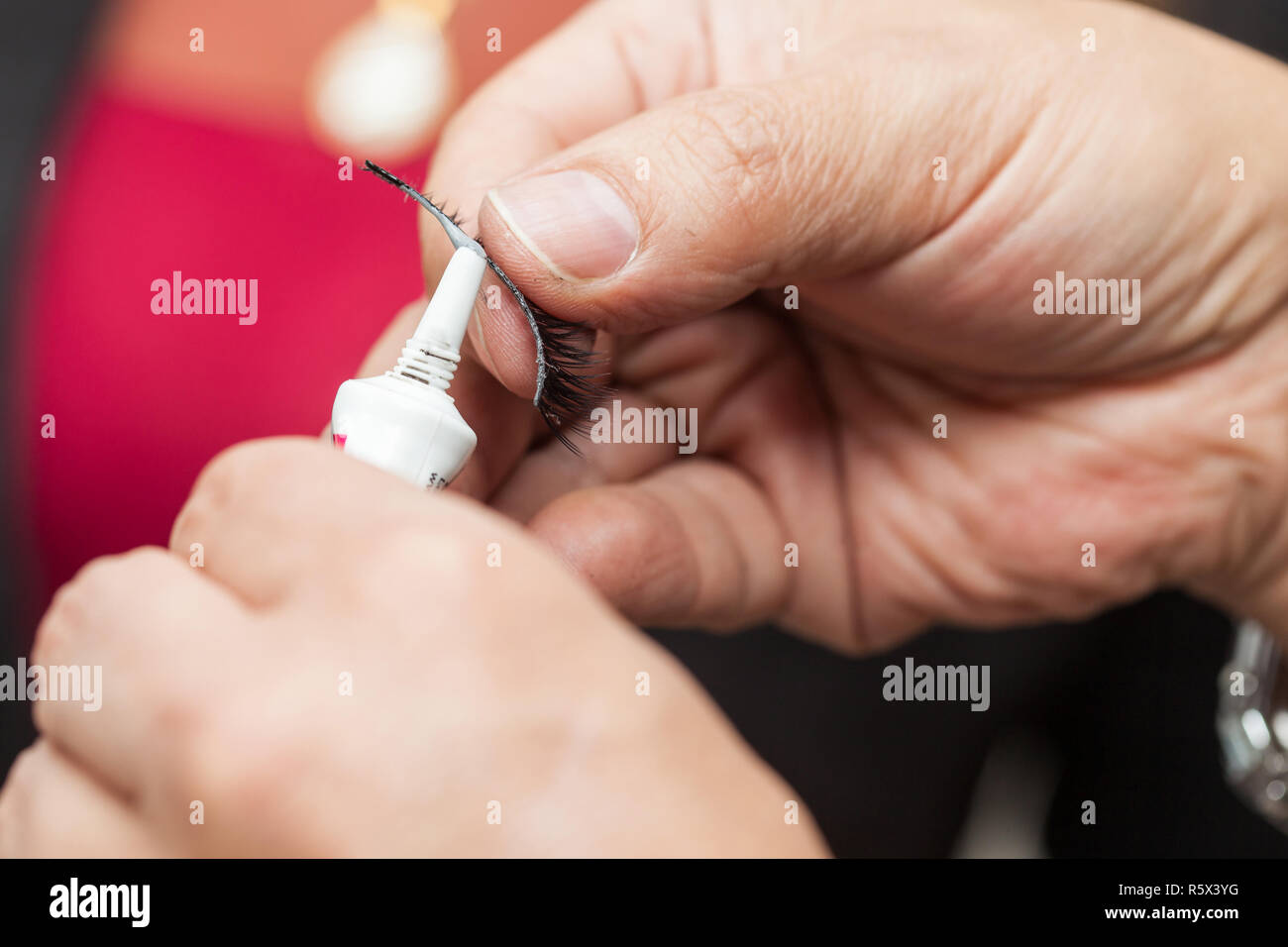 Nahaufnahme von einem Make up artist Hände Auftragen kosmetischer Leim auf falsche Wimpern Stockfoto