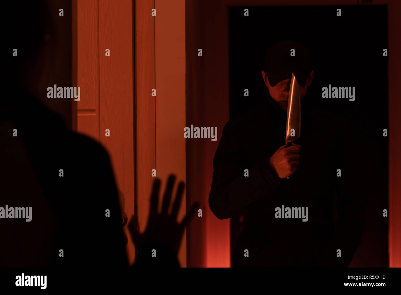 Bild der Dieb mit Machete und Mann mit hands up in dunklen Zimmer Stockfoto