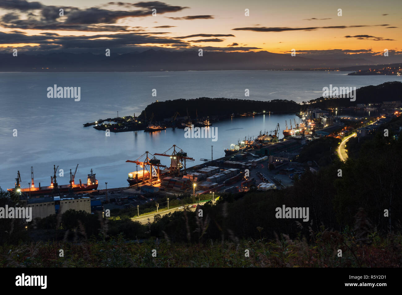 Nacht Blick von oben auf die Frachtschiffe und Kriegsschiffe in Anchorage an den Piers in kommerziellen Hafenbahnhof von Petropawlowsk-kamtschatski Stadt am Ufer des Pazifischen Ozeans Stockfoto