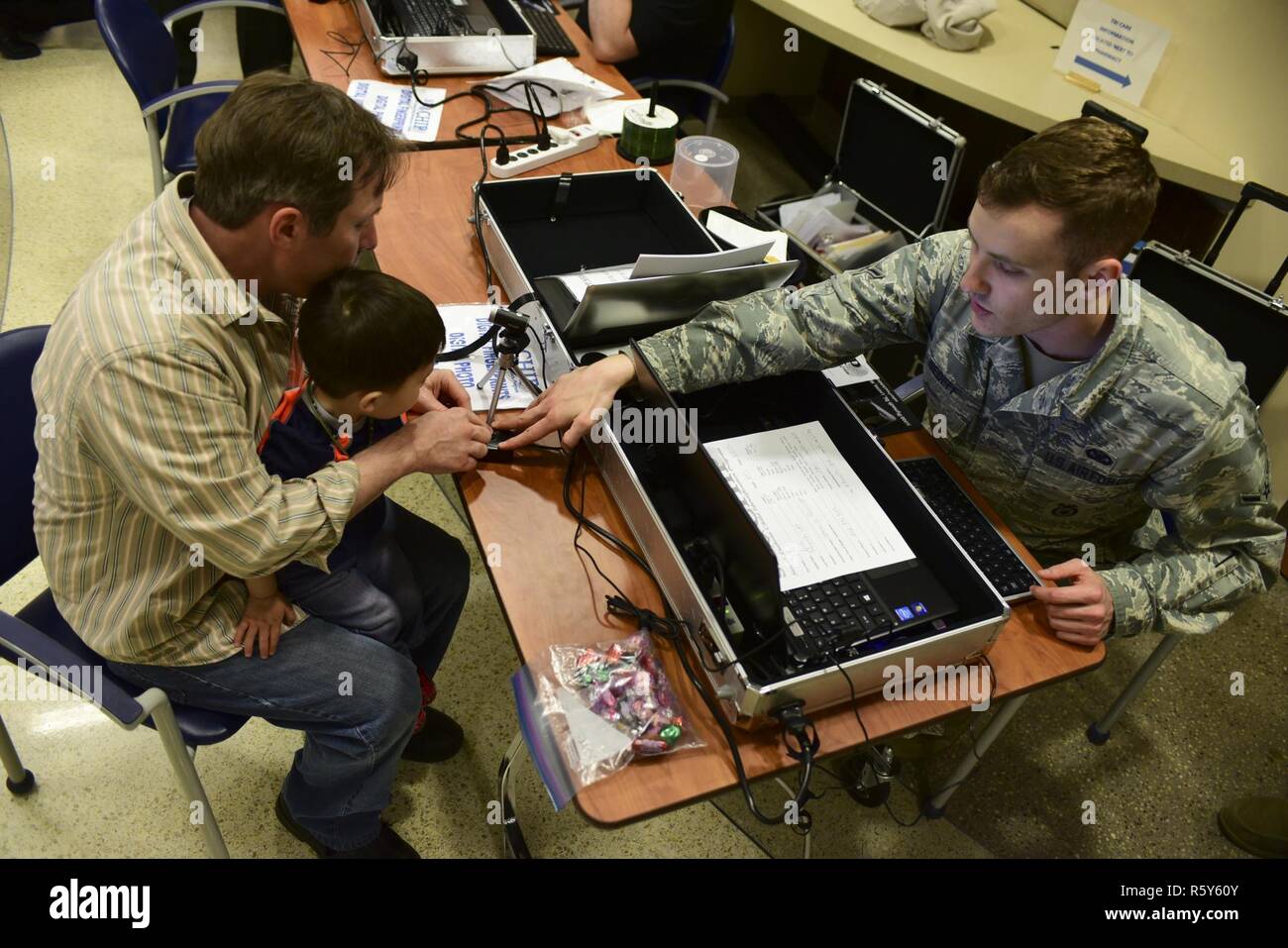 Steven Romehildt hilft, sein Sohn, Paul, während die 2017 Kinder Messe innerhalb der 28. Medical Group Ellsworth Air Force Base, S.D., 20. April 2017 seinen Fingerabdruck scannen. Eltern erhalten eine Kind-Identifikation-Kit zur Strafverfolgung, die ihr Kind zu finden, wenn sie verloren werden zu helfen. Stockfoto