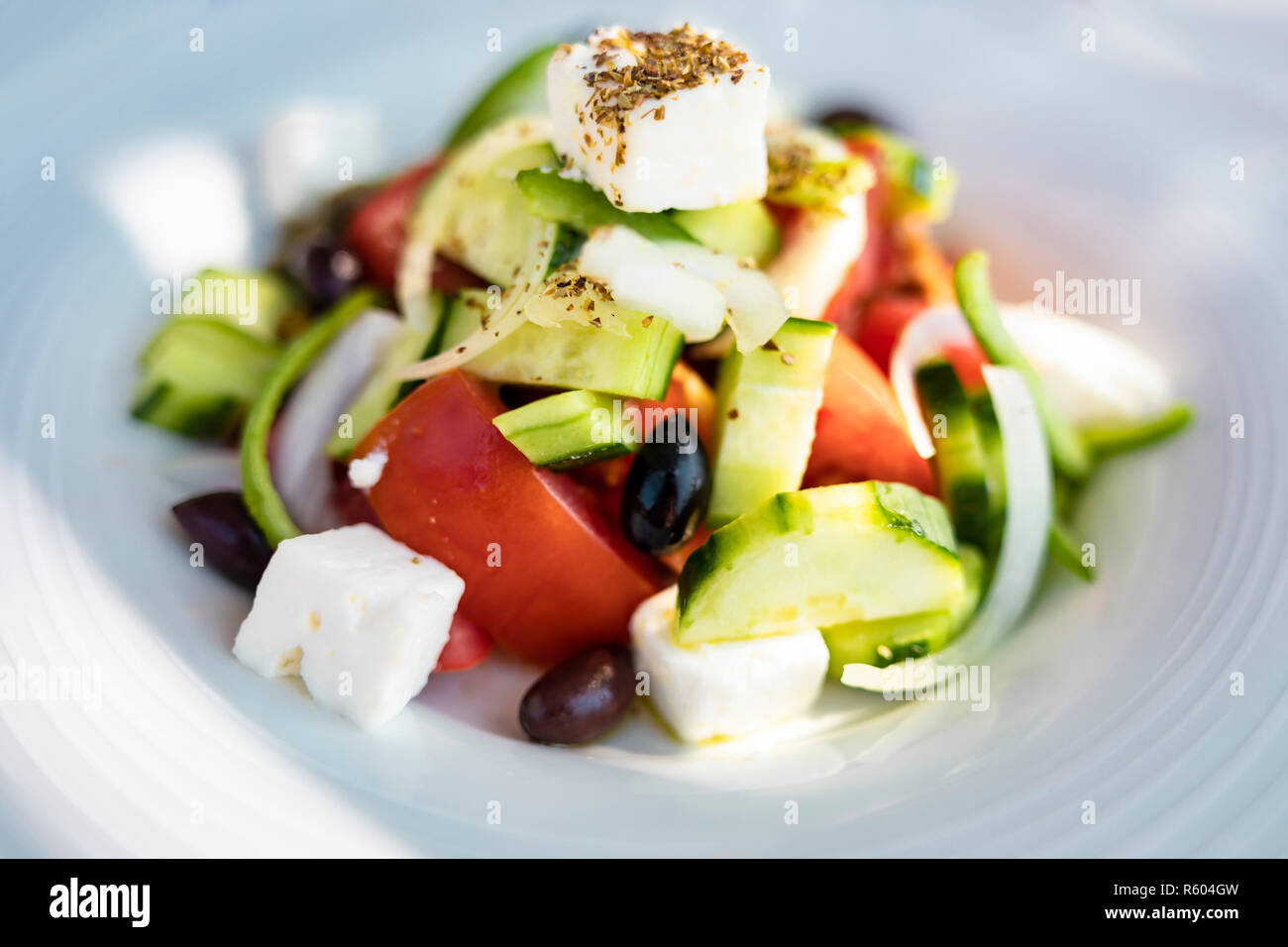 Nahaufnahme von einer Platte mit einem griechischen Salat aus Schichten von Tomaten und Gurken, Oliven, Würfeln Feta Käse und Kräutern. Stockfoto