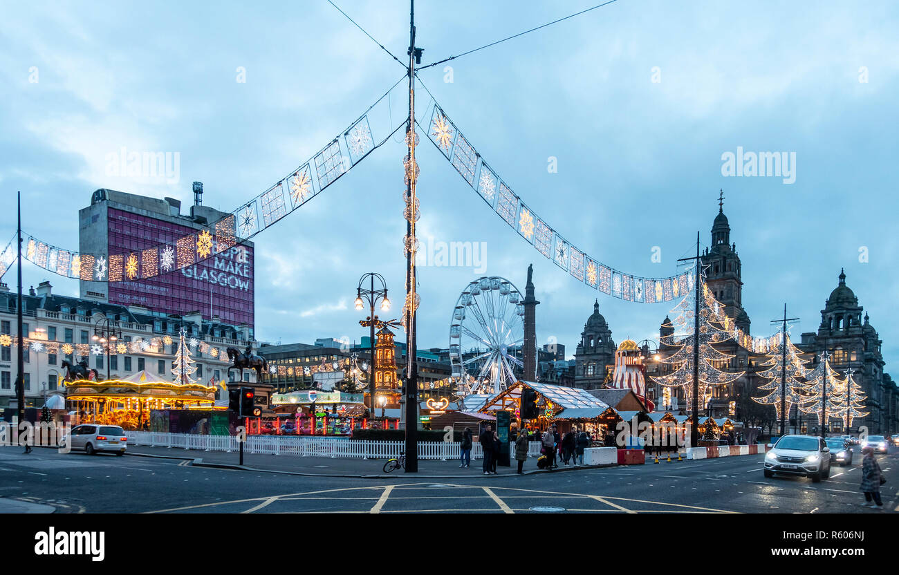 Der Weihnachtsmarkt auf dem George Square im Zentrum von Glasgow. Riesenrad, Karussell, Weihnachtsschmuck, Fußgänger und Verkehr, Schottland, Großbritannien. Stockfoto