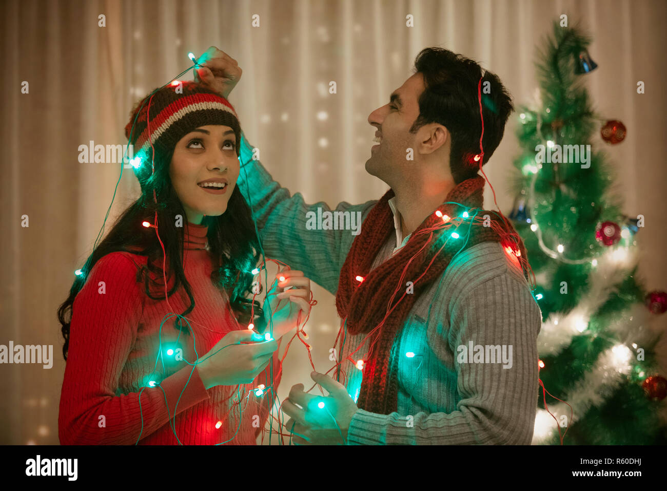 Junges Paar verpackt fairy Licht an Weihnachten feiern Stockfoto