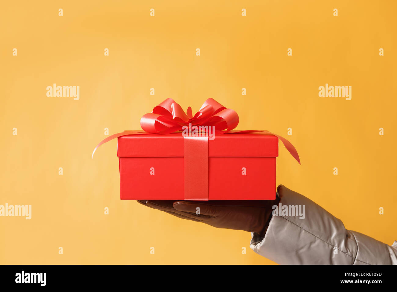 Close-up Teilansicht der Mann mit roter Geschenkbox auf gelben Hintergrund. Geschenk, das Konzept Stockfoto