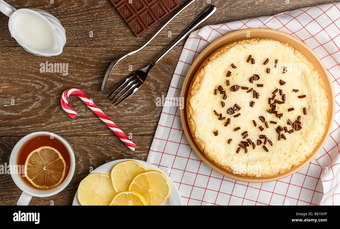 Hausgemachter Käsekuchen mit Schokolade, Tee mit Zitrone und Weihnachten Candy auf einer hölzernen Hintergrund. Ansicht von oben Stockfoto