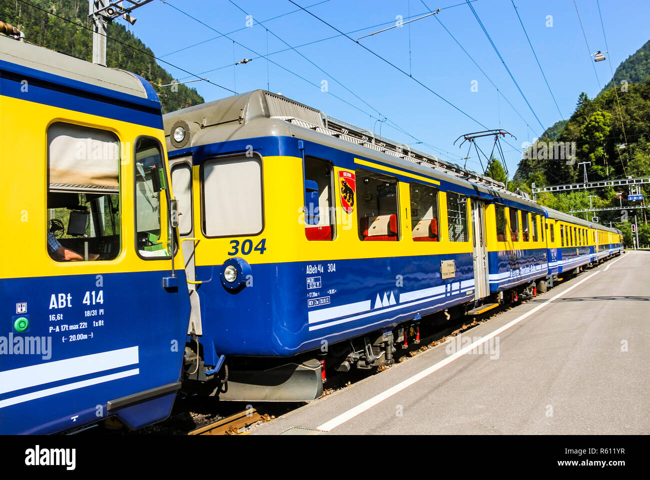 Grindelwald, Schweiz - Juli, 2013: Gelb und Blau Berner Oberland Bahn hält am Bahnhof Grindelwald Plattform Stockfoto