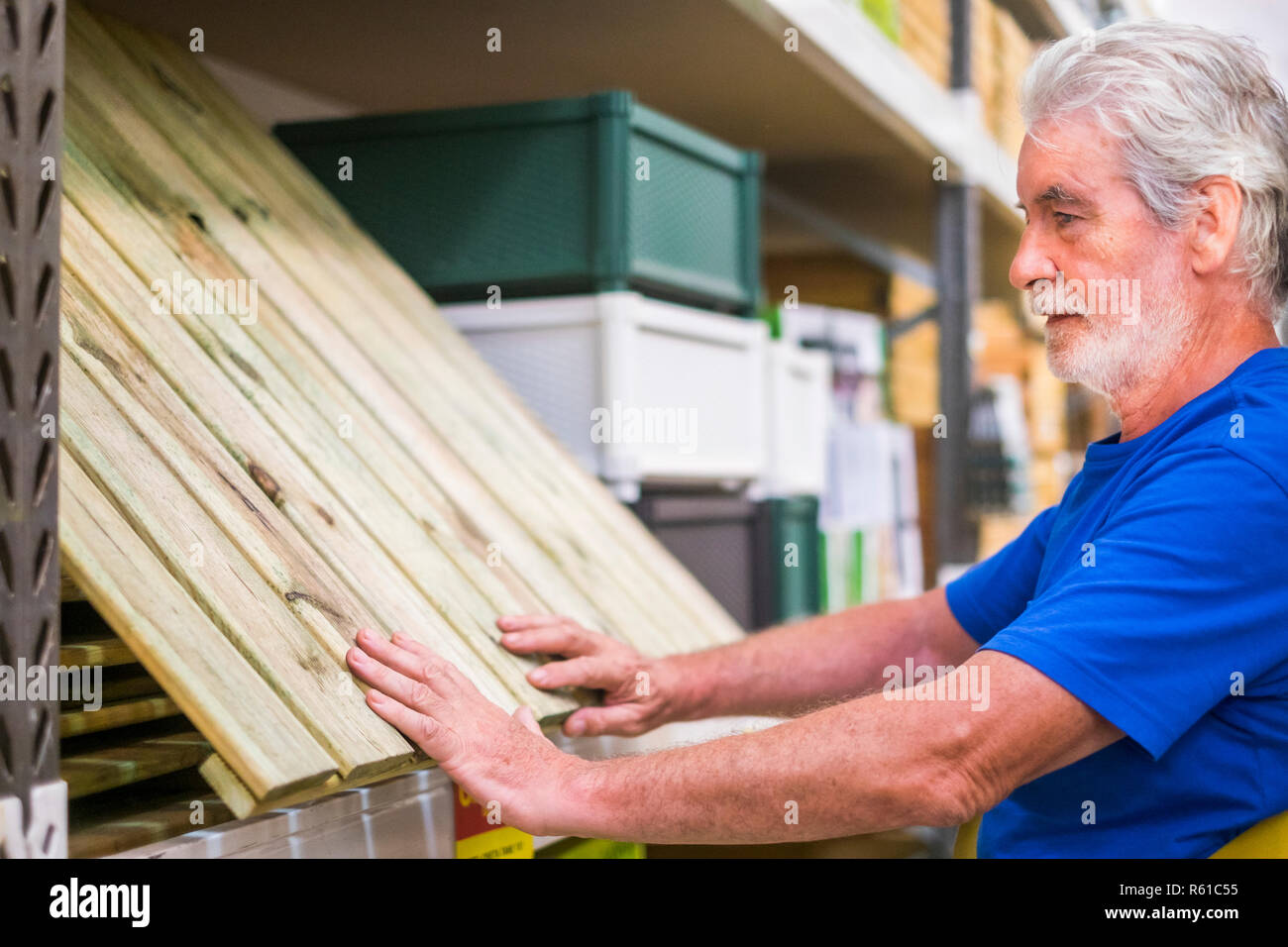 Kaukasische mann Artikel in Hardware Store wählen Holzboden wie Paletten Möbel oder Masse zu Hause zu bauen - Business Konzept für Rentner Stockfoto