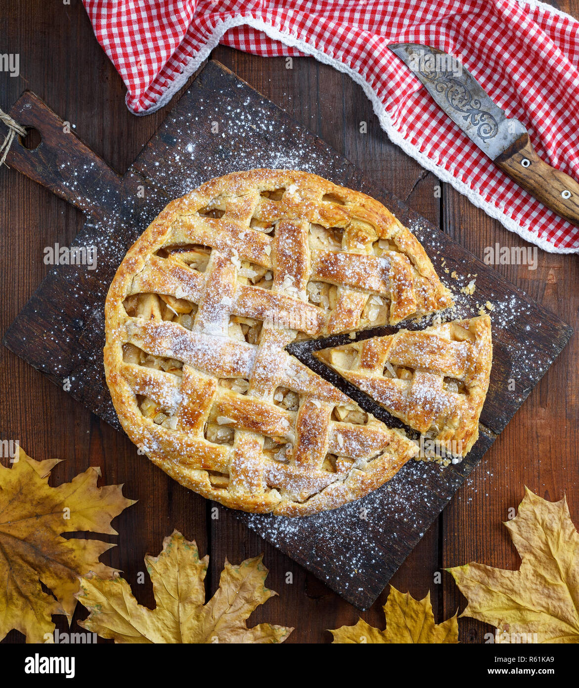 Ganze runde Apfelkuchen auf einem rechteckigen alte braune Board gebacken, Holztisch, Ansicht von oben Stockfoto