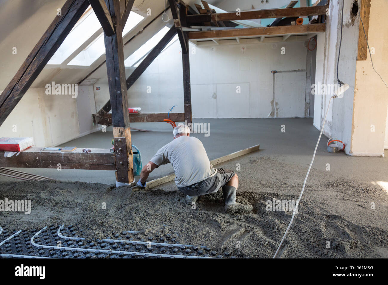 Arbeiter Nivellierung Sand und Zement Estrich auf Fußbodenheizung. Stockfoto