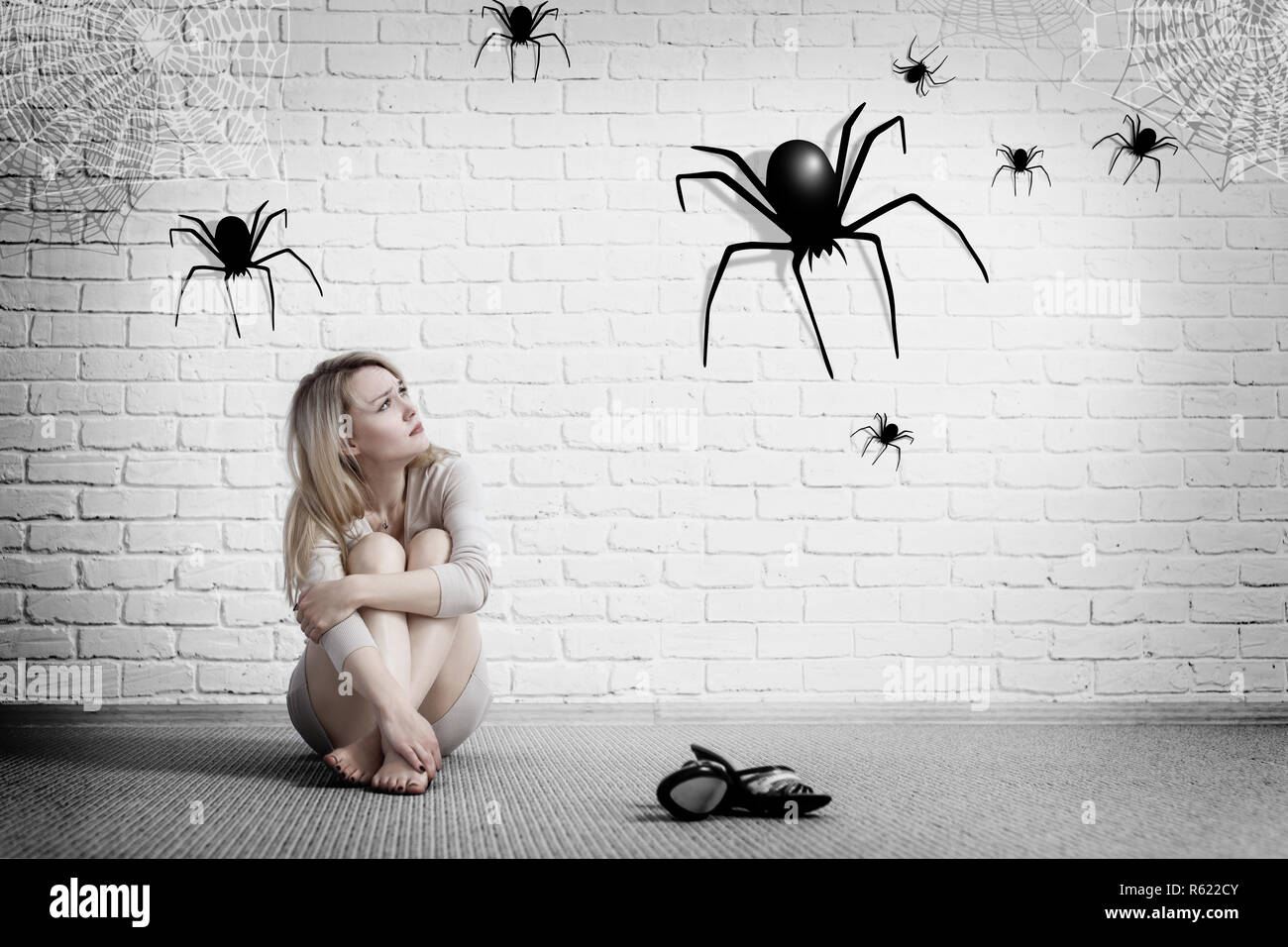 Frau sitzt auf dem Boden und Suchen auf imaginäre Spider. Stockfoto