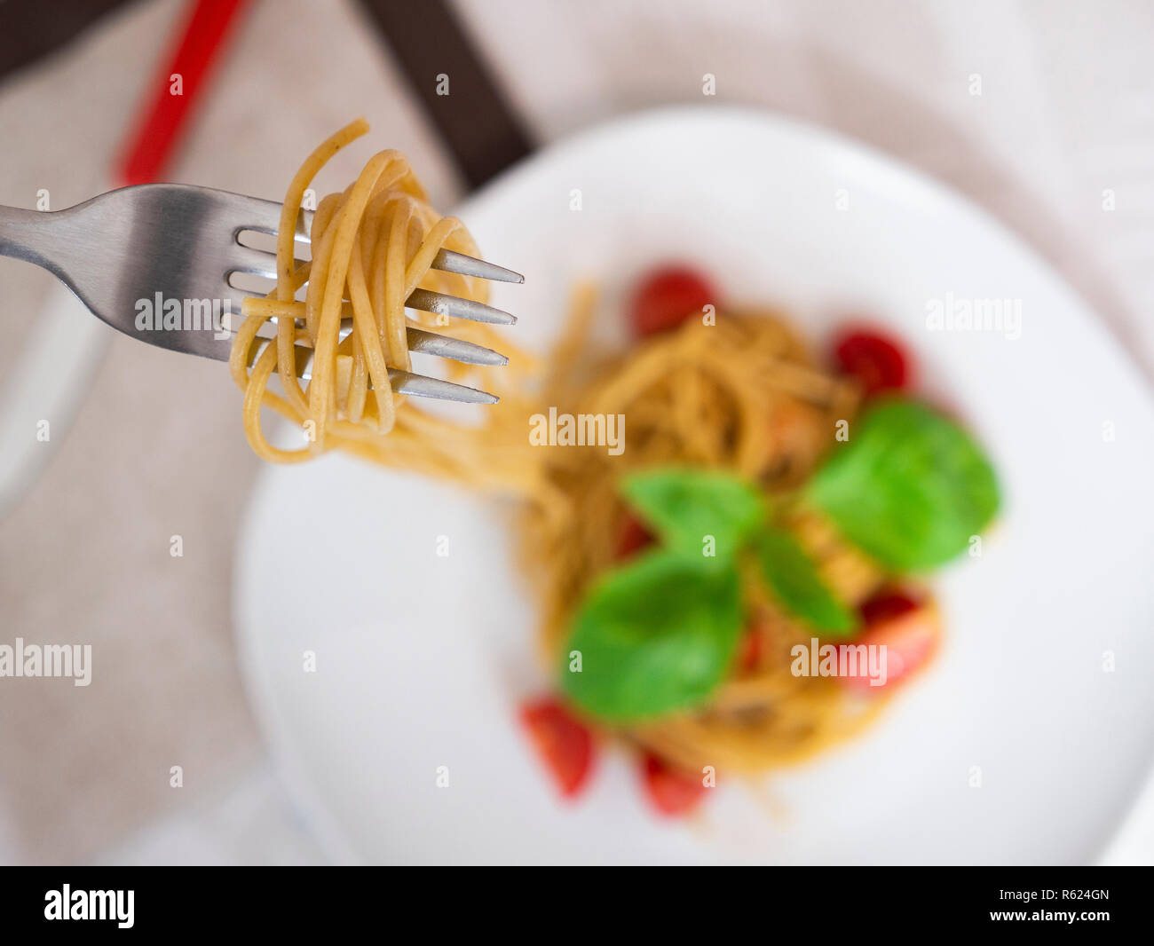 Junge Frau essen Vollkorn Spaghetti mit Tomaten und Basilikum Stockfoto